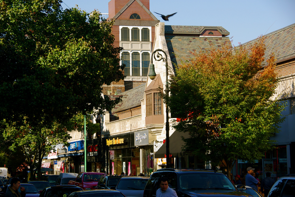 Sunny commercial street with Tudor-style storefronts on 82nd Street in Jackson Heights, Queens