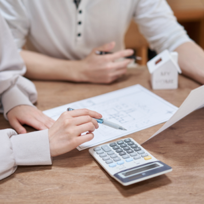 two people at a table looking at numbers with a calculator and house