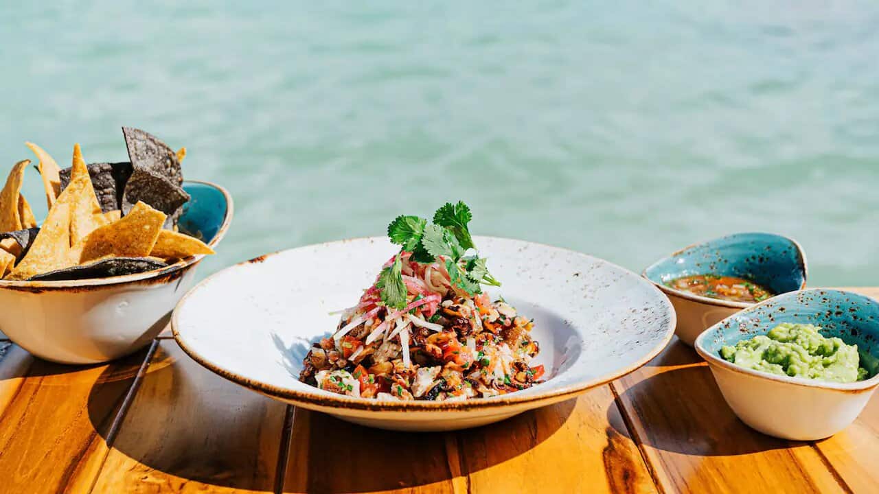 A luxury fine brunch table setup on a white sand beach in the Riviera Maya at sunset.