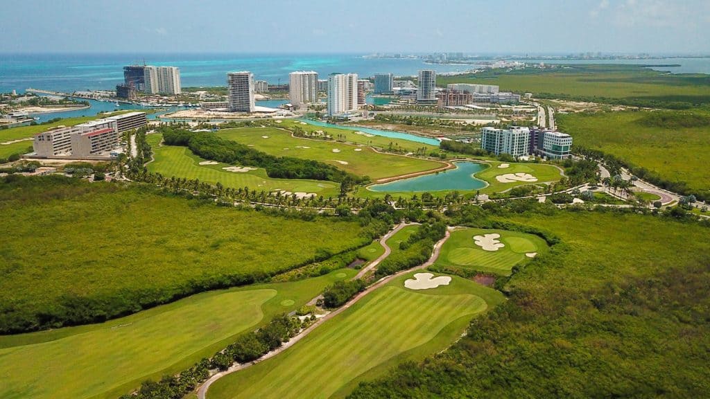 Panoramic view of a luxury house overlooking a lush green golf course in Cancun