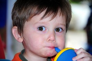 Image is a close up of a young boy drinking out of a straw.