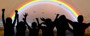 Image is a rainbow with children in front of it, cast in shadow. Image is a rainbow with children in front of it, cast in shadow.