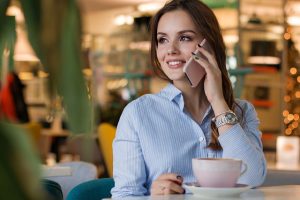 Image is a woman on the phone sitting in a cafe.