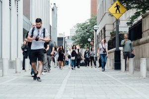 Image is people walking along a street downtown in a city.