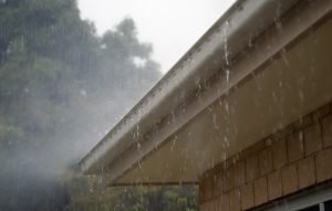Image is a rain gutter on a home overflowing.