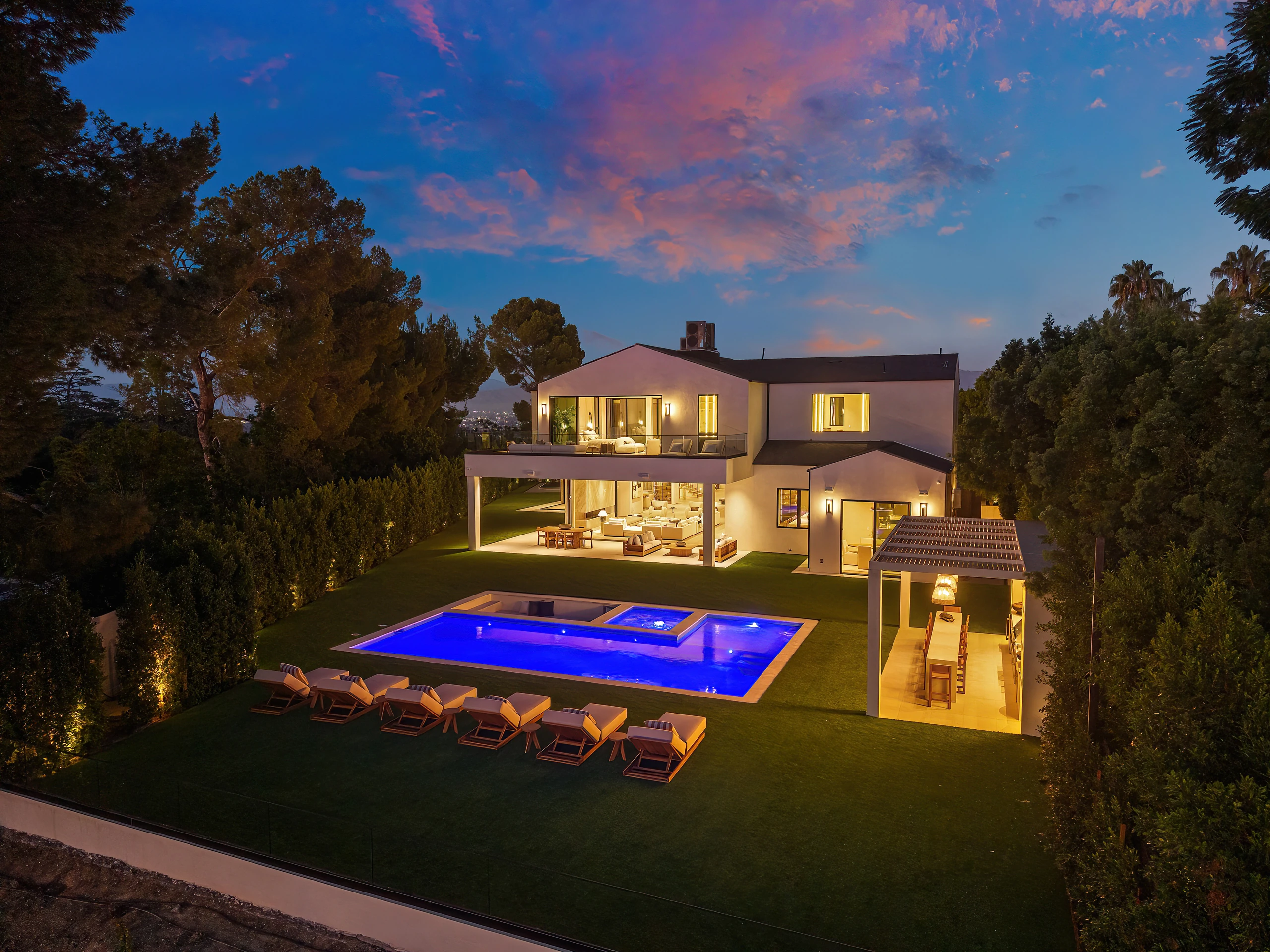 The illuminated residence and pool viewed from above