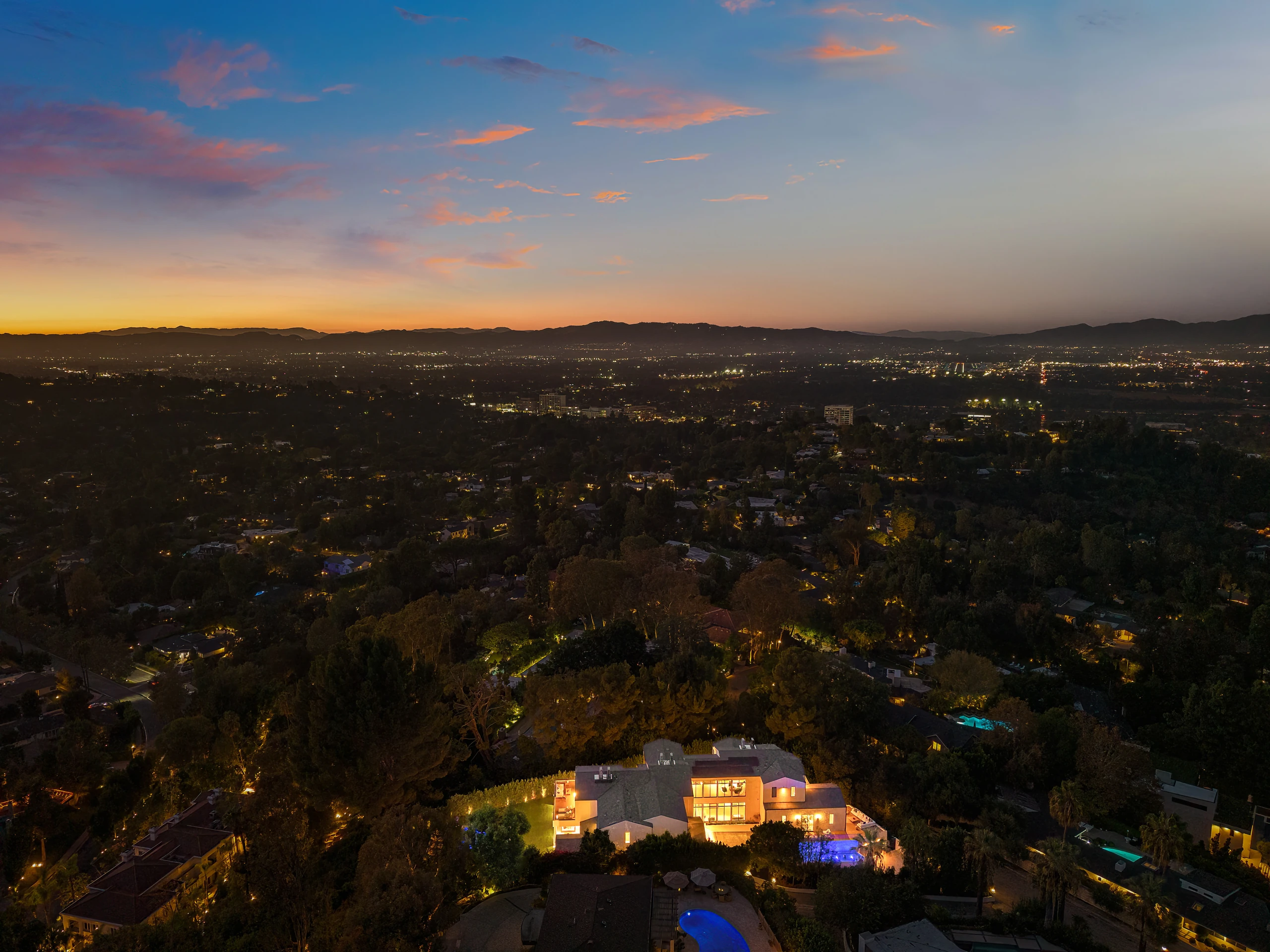 The illuminated estate and surrounding hills at dusk