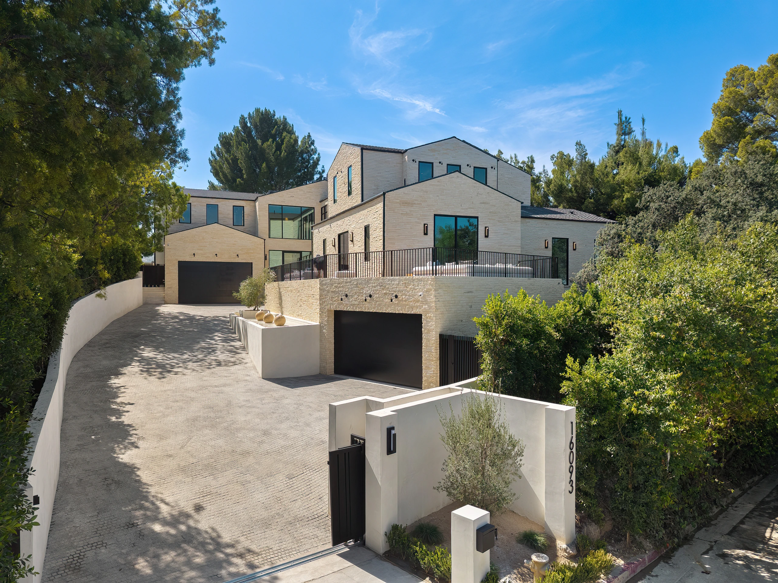 The stone-clad residence and driveway in daylight