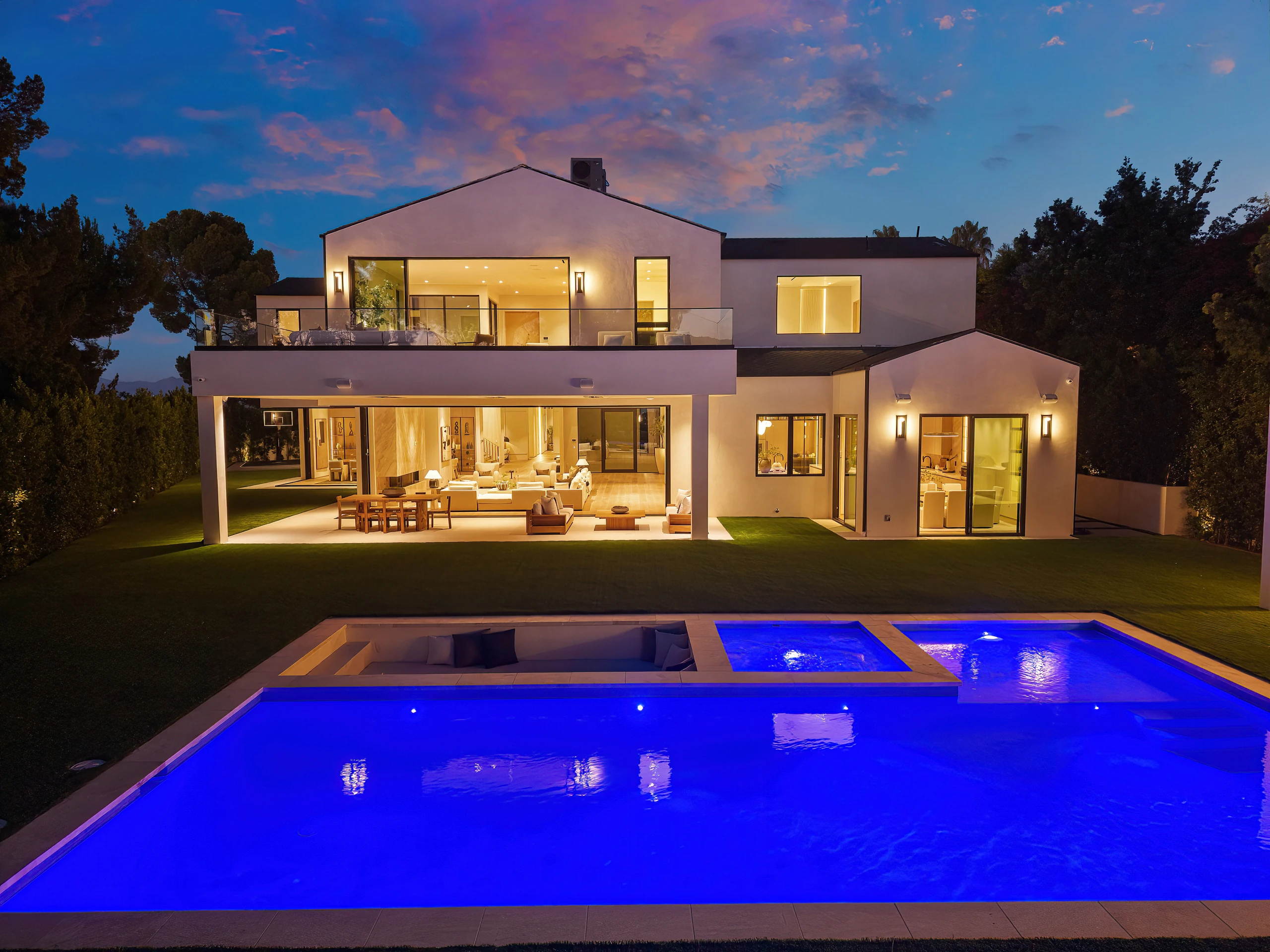The illuminated residence and blue pool at night