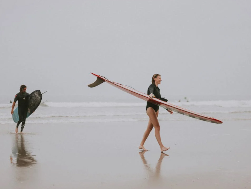 Woman walking on beach with surfboard