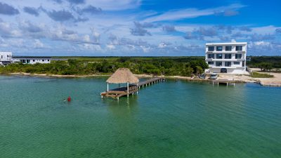 Aerial view of 0.2-acre beachfront property at Secret Beach, Ambergris Caye, showing road access and private pier