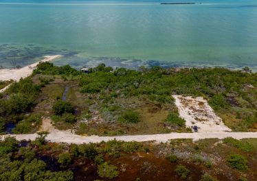 Aerial view of second-row beach lot near Secret Beach, Ambergris Caye, Belize, showing lot boundaries, turquoise waters, and surrounding development.