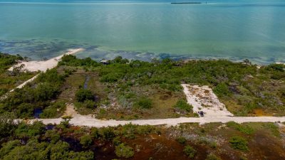 Aerial view of second-row beach lot near Secret Beach, Ambergris Caye, Belize, showing lot boundaries, turquoise waters, and surrounding development.