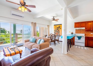 Living room of Mara Laguna condo with large windows overlooking the Caribbean Sea on Ambergris Caye, Belize.