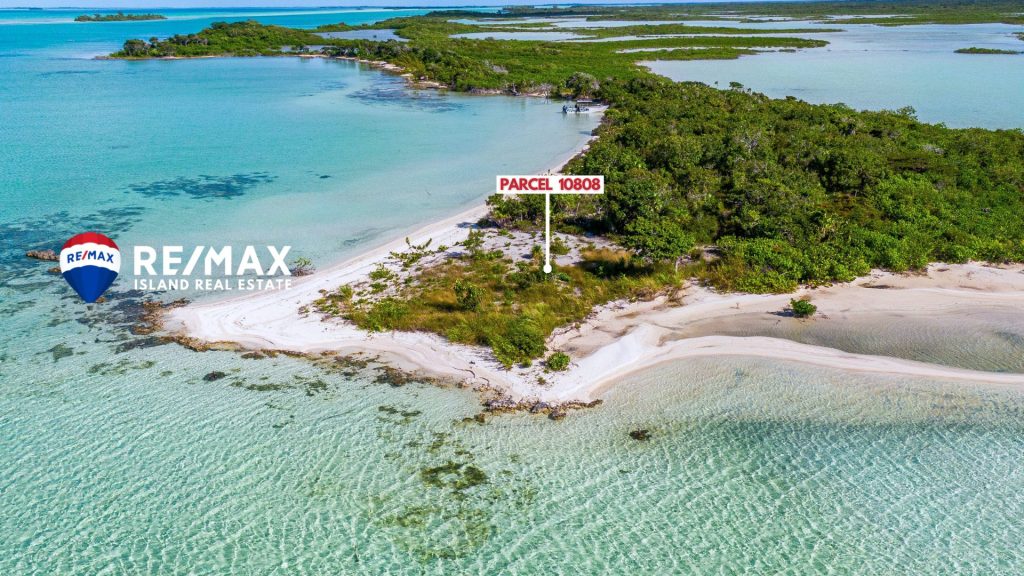 Aerial drone view of Parcel 1808 beachfront point lot on the west side of Ambergris Caye Belize, showing clear turquoise water wrapping around a unique 90-degree white sand shoreline with native green vegetation.