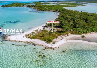Aerial drone view of Parcel 1808 beachfront point lot on the west side of Ambergris Caye Belize, showing clear turquoise water wrapping around a unique 90-degree white sand shoreline with native green vegetation.
