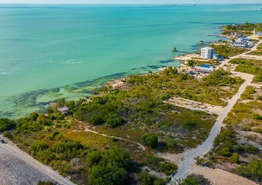 Aerial view of a 64-foot beachfront parcel facing clear Caribbean waters and dirt access roads at Secret Beach