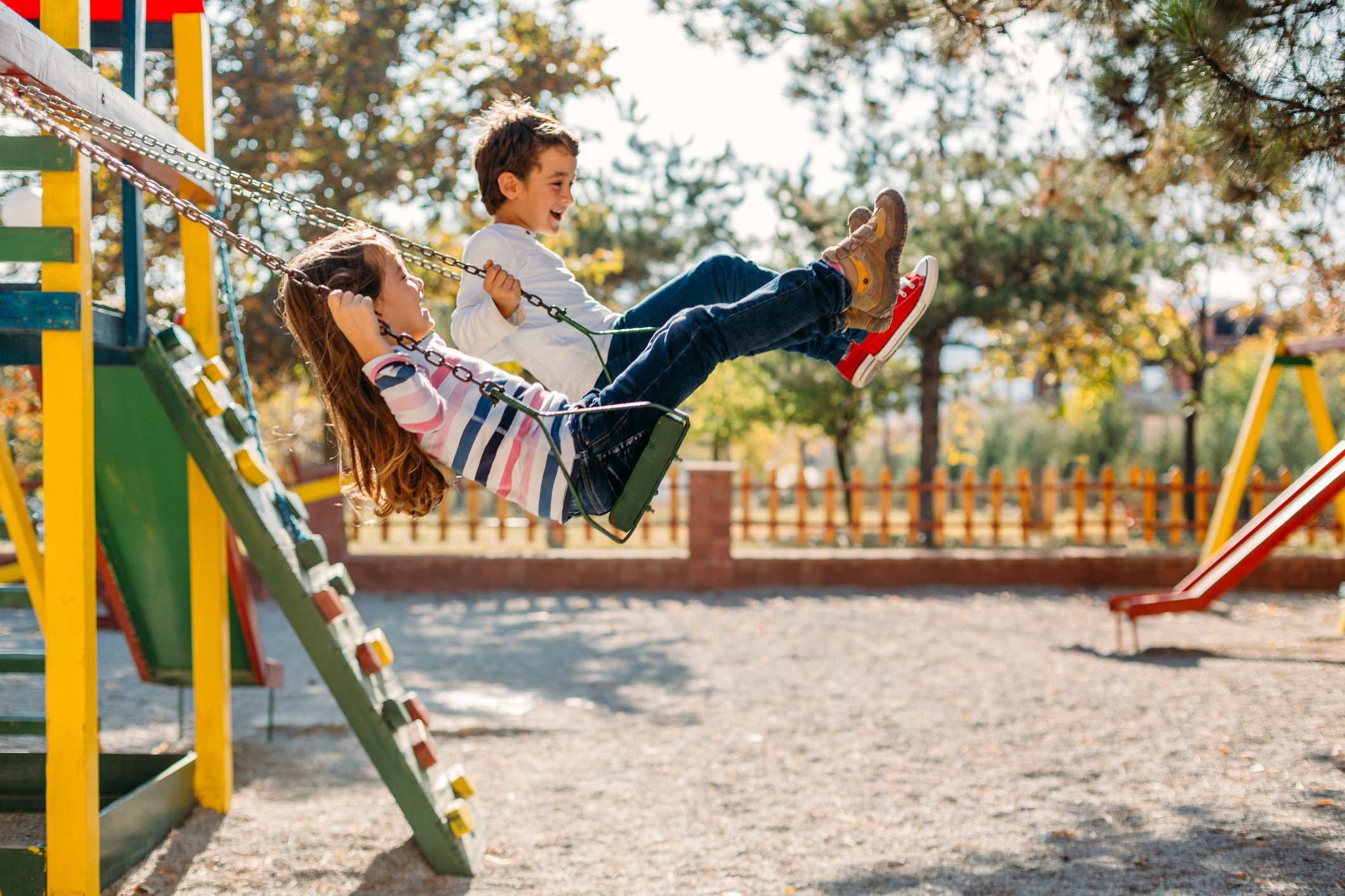 Children playing on swings at a family-friendly playground in the Cotswold Charlotte community