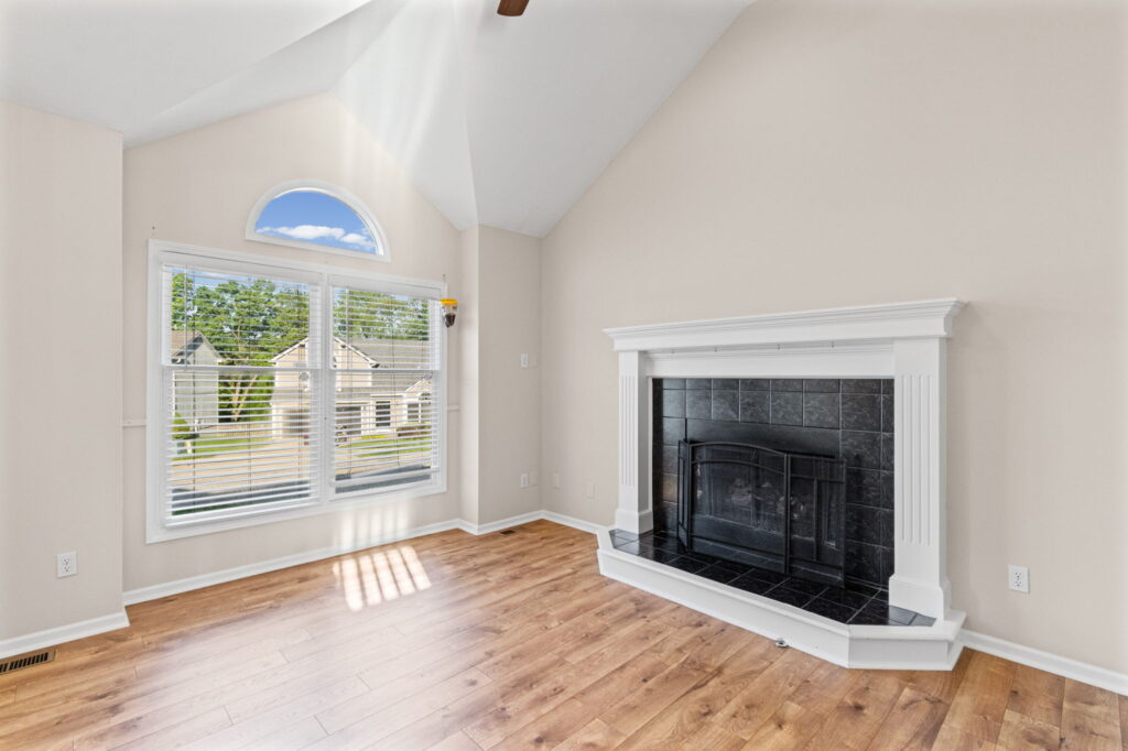 Living room with vaulted ceilings, a gas fireplace, and a large front window at 7205 N Hickory Street