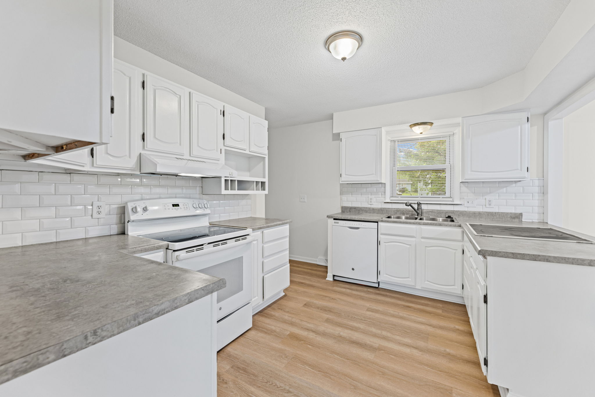 Renovated kitchen with white cabinetry, subway tile, and a breakfast bar — 119 Sherri Lane, Excelsior Springs, MO