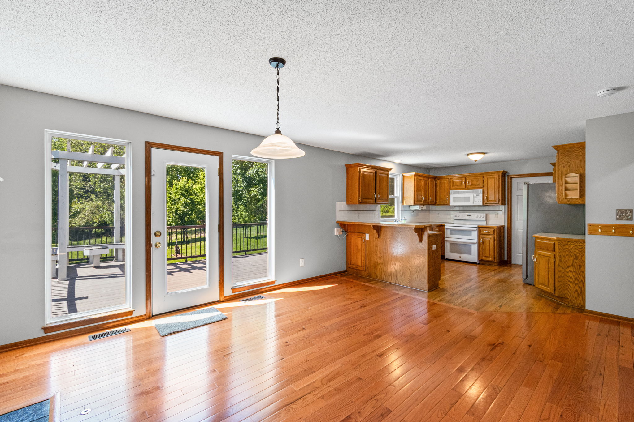 Kitchen open to the hearth room with hardwood floors and deck access at 15801 E 2nd Street S, Independence, MO