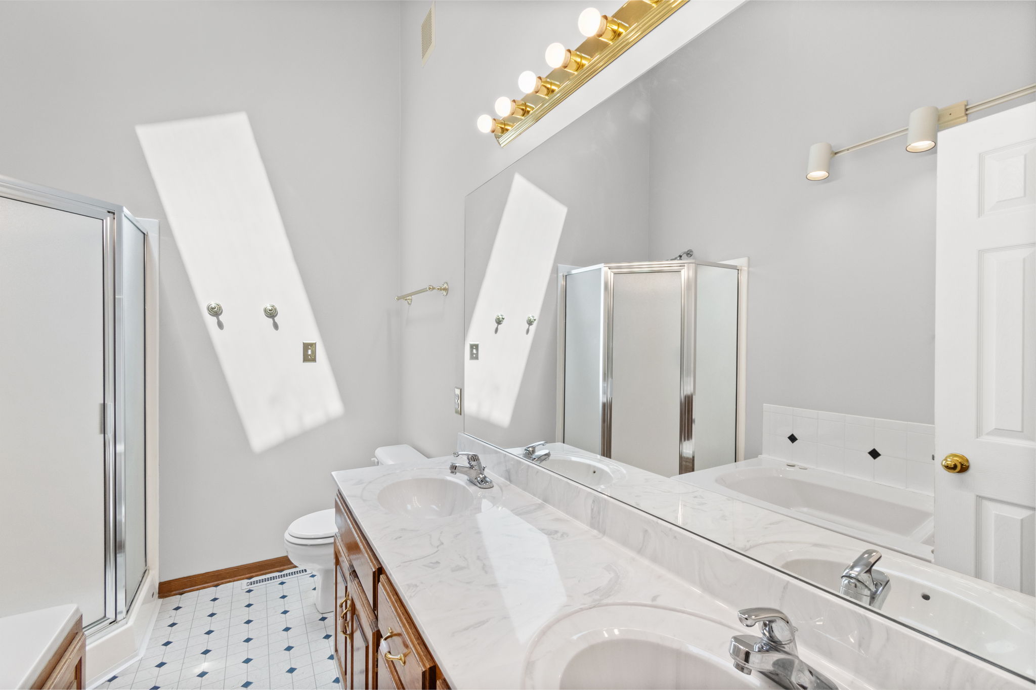 Primary bath with skylights, double vanity and separate tub and shower at 15801 E 2nd Street S, Independence, MO