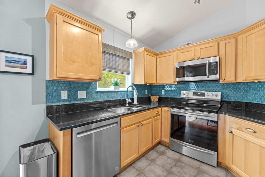 Kitchen with granite counters, tile backsplash, and updated appliances