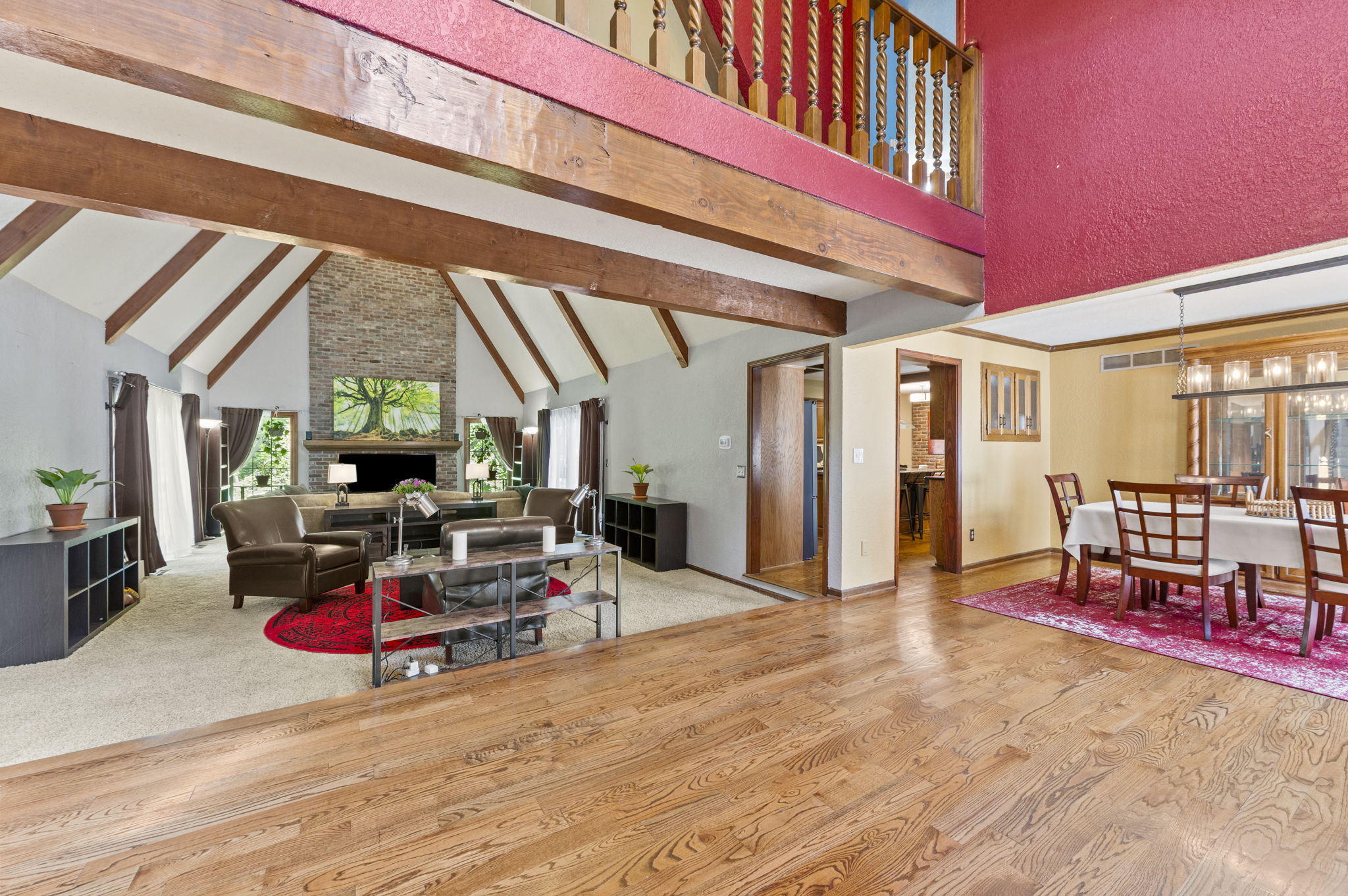 Open living and dining area with a vaulted wood-beam ceiling and an open catwalk above