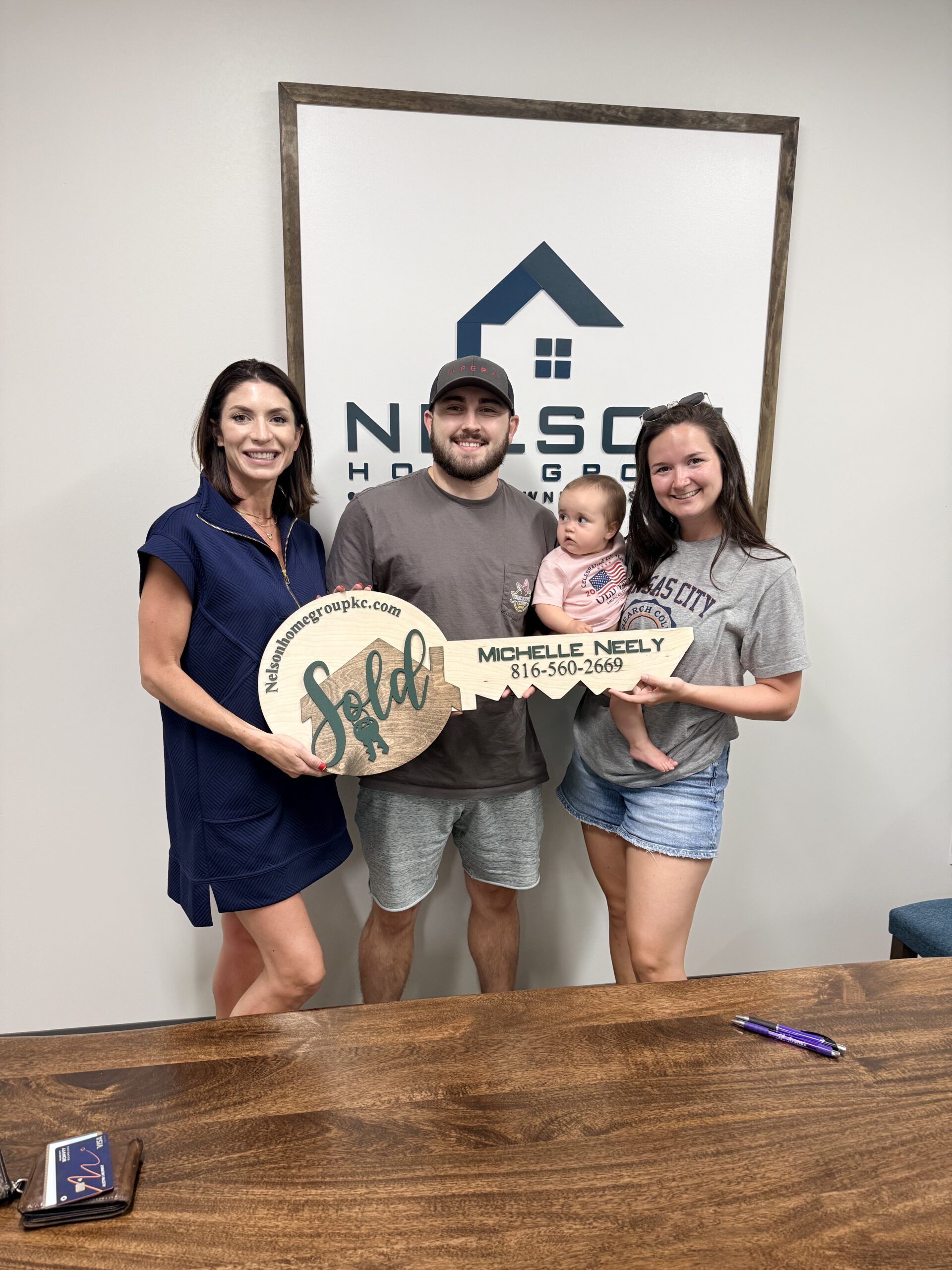 Austin and Morgan with agent Michelle Neely holding the Nelson Home Group SOLD key