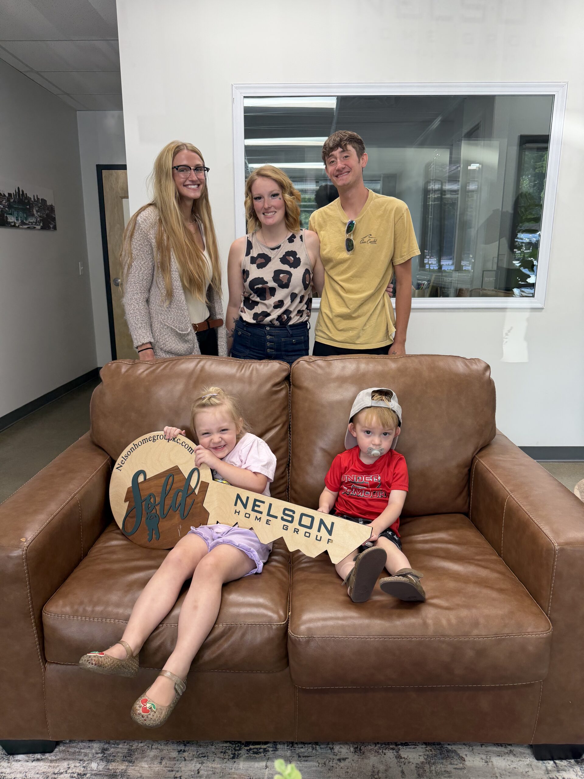 Ashton and Candace with their kids and agent McKenna Holdshoe holding the Nelson Home Group sold key at closing