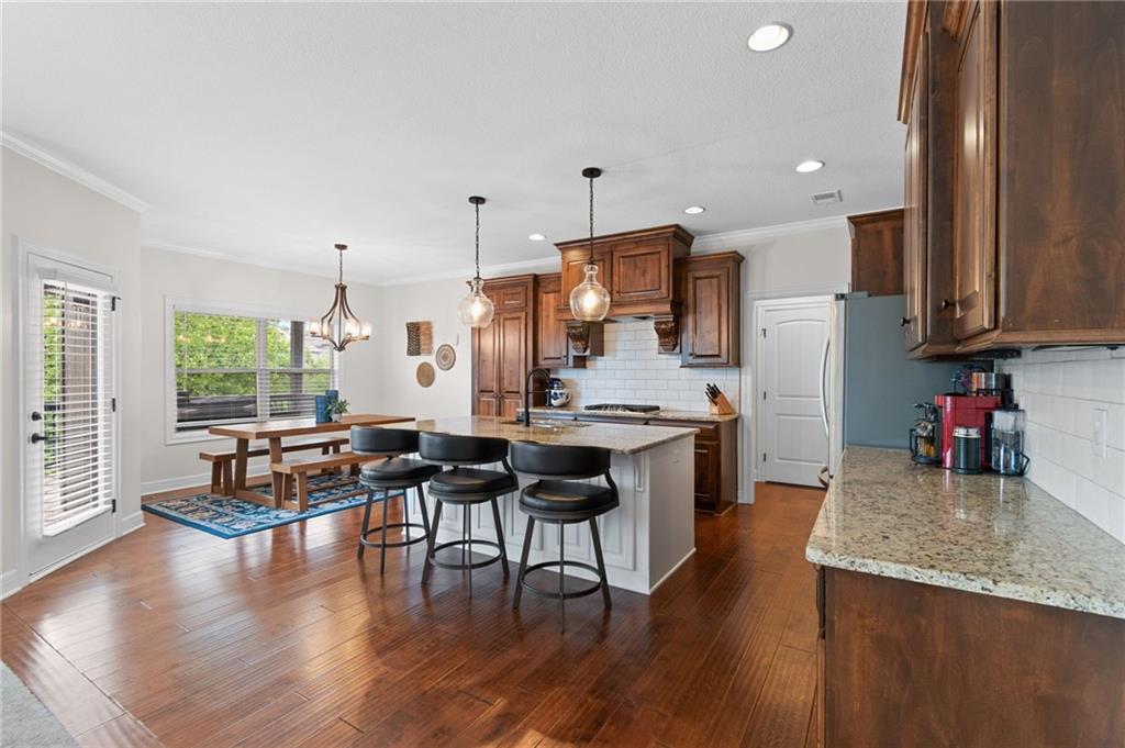 Kitchen with granite countertops, stained cabinetry, and island seating