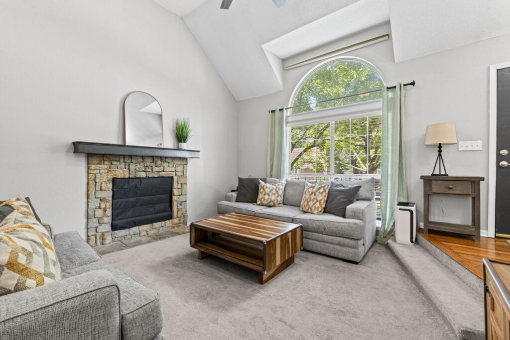 Living room with vaulted ceiling and stone fireplace at 1126 E Charlotte Town Road, Olathe, KS