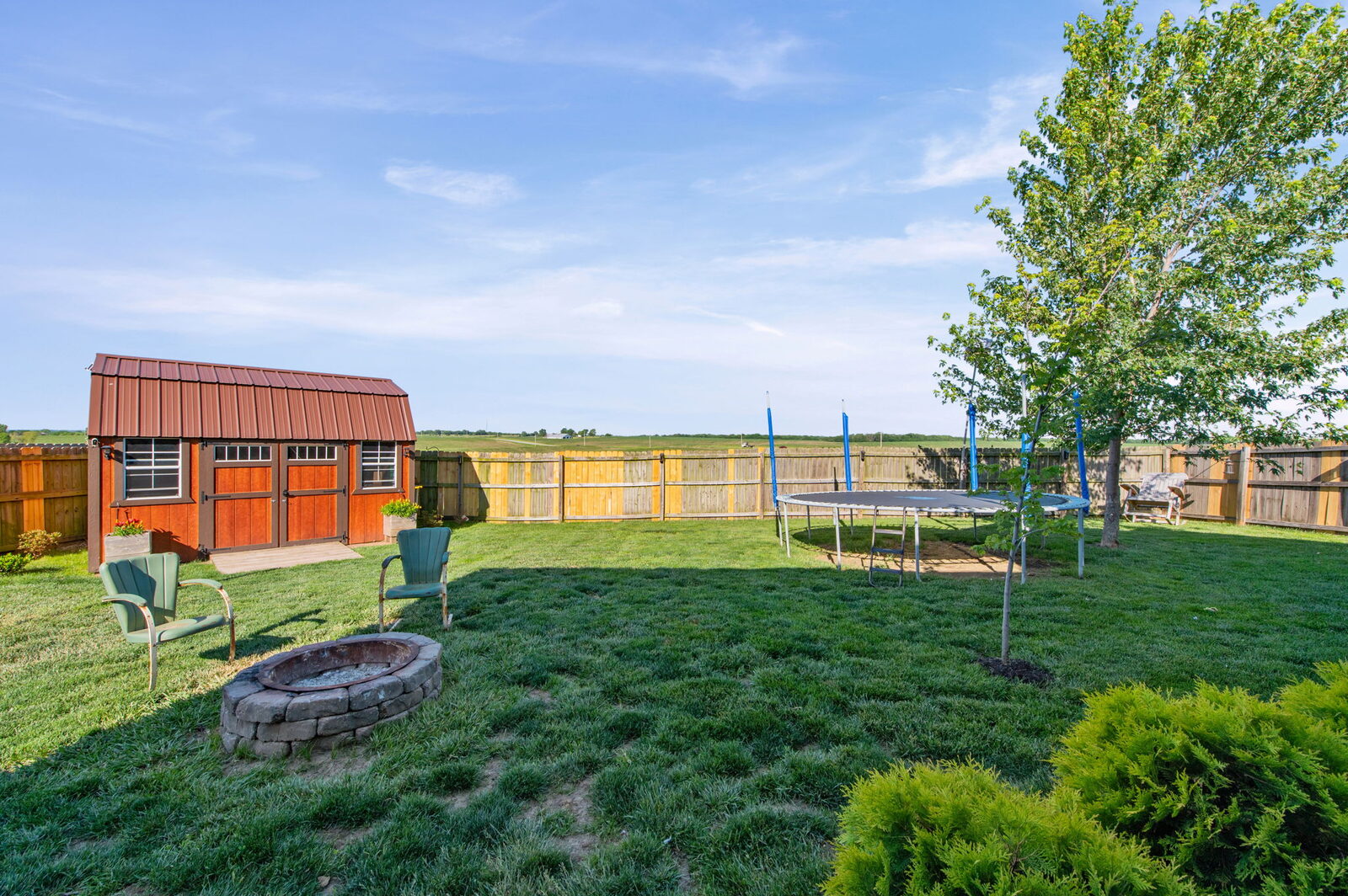 Privacy-fenced backyard with storage shed and fire pit at 19204 Corbyn Lane, Smithville, MO