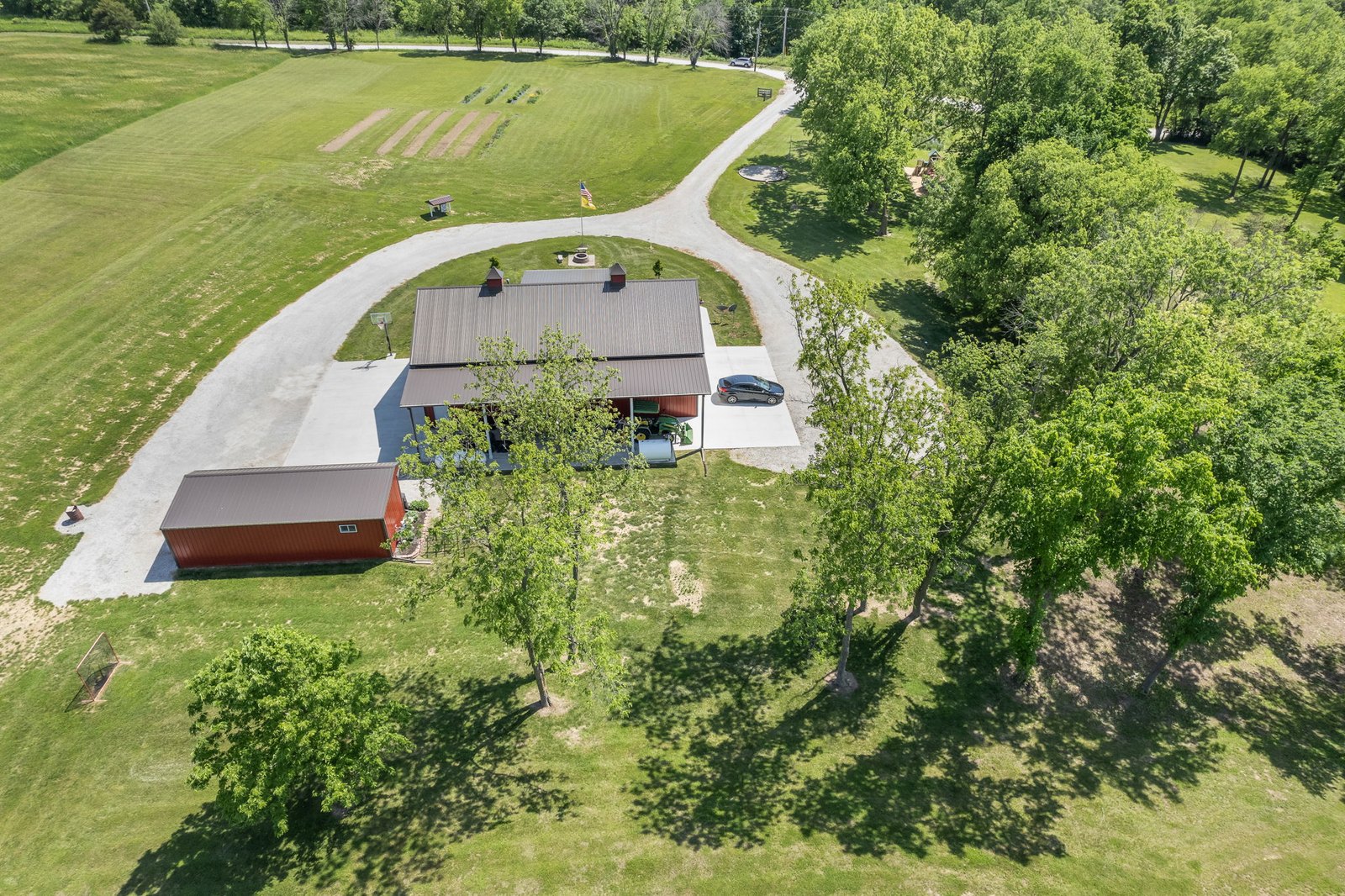 Aerial view of the 7.69-acre property showing the home, circle drive, and separate utility outbuilding