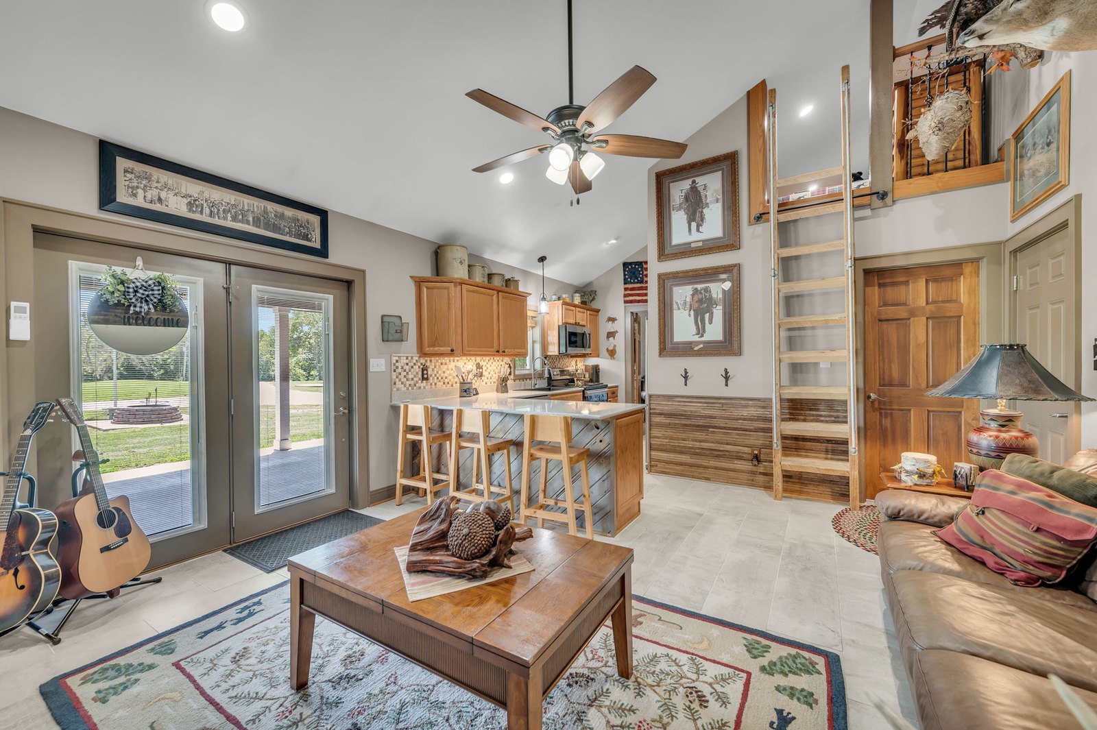 Open-concept living room with vaulted ceiling and French doors to the patio