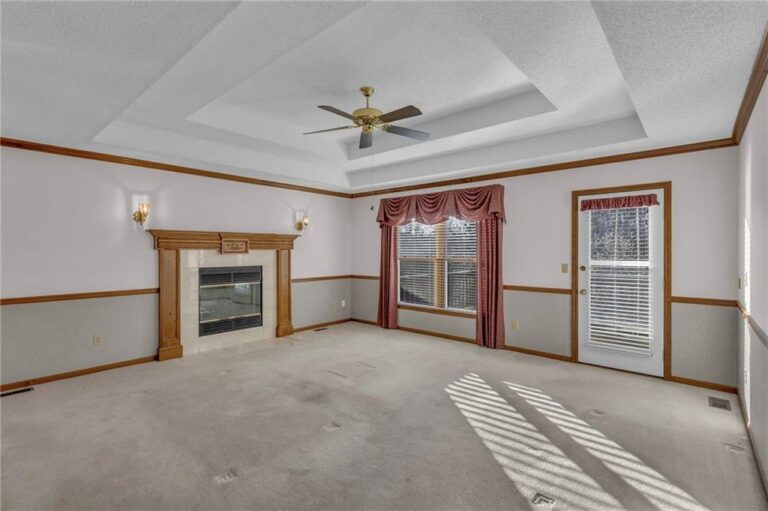 Living room with gas fireplace, tray ceiling and a door to the elevated deck at 7020 N Garfield Avenue in Gladstone, Missouri