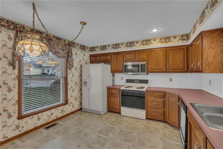 Kitchen with original oak cabinets, laminate counters and a window over the dining area at 7020 N Garfield Avenue, Gladstone, Missouri