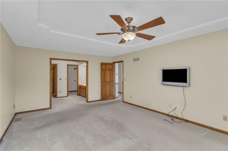 Main-level primary bedroom with tray ceiling, ensuite bathroom and walk-in closet at 7020 N Garfield Avenue, Gladstone, Missouri