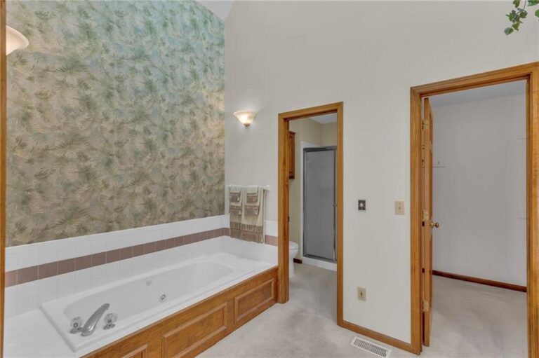 Primary bathroom with jetted tub, separate glass shower and vaulted ceiling at 7020 N Garfield Avenue in Gladstone, Missouri