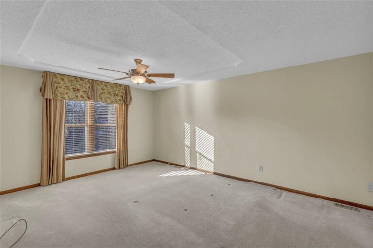 Second upstairs bedroom suite with tray ceiling and ceiling fan at 7020 N Garfield Avenue, Gladstone, Missouri
