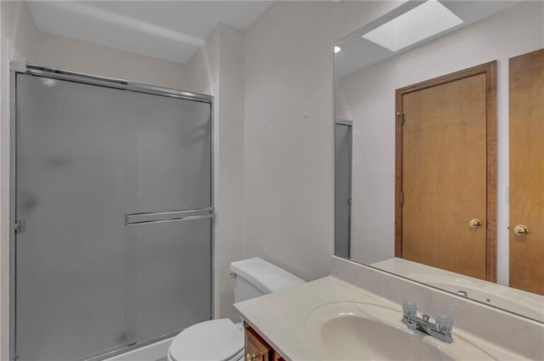 Full bathroom with a glass shower enclosure and single vanity at 7020 N Garfield Avenue, Gladstone, Missouri