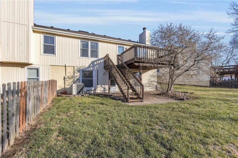 Rear exterior with elevated deck, stairs and fenced yard at 7020 N Garfield Avenue, Gladstone, Missouri