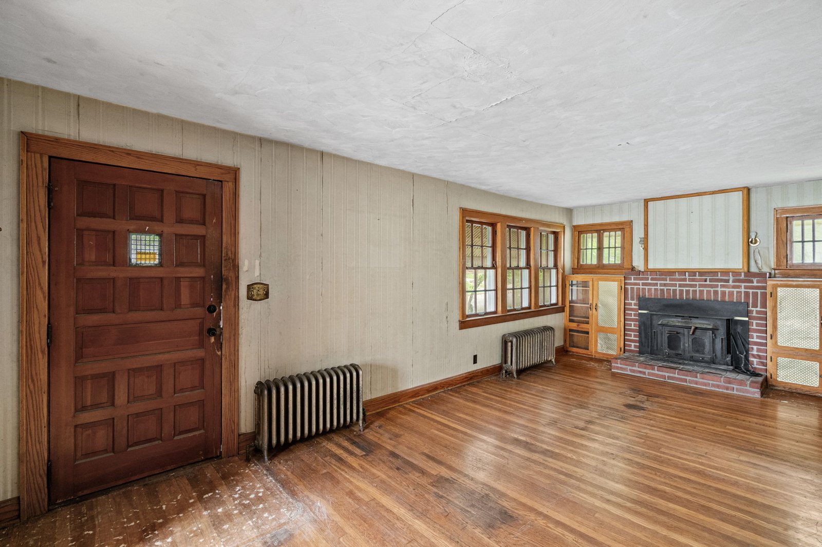 Living room in the Epperson Place bungalow with a brick fireplace flanked by original built-in shelving and hardwood floors