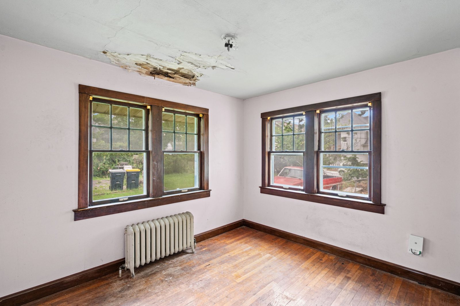 Upstairs bedroom in this Epperson Place bungalow with original hardwood floors and damaged plaster ceiling
