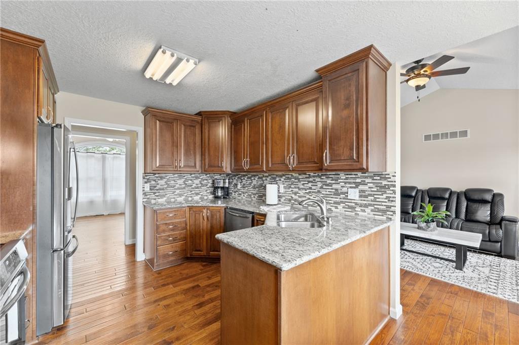 Kitchen with granite counters, a glass tile backsplash, wood cabinets and stainless appliances in a ranch home in Cameron, Missouri