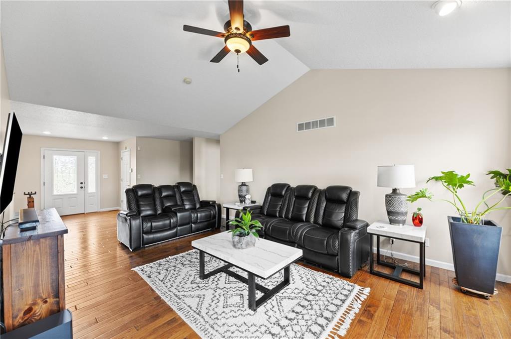 Living room with a vaulted ceiling and hardwood floors open to the front entry in a ranch home in Cameron, Missouri