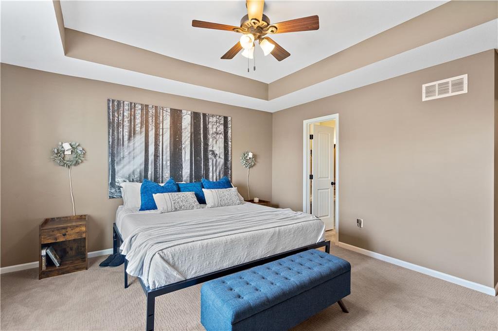 Main-floor primary bedroom with a tray ceiling in a Weston, MO ranch home