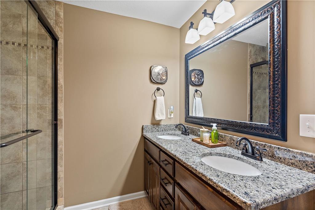 Primary bathroom with a dual vanity and tiled shower in a Weston, MO ranch home