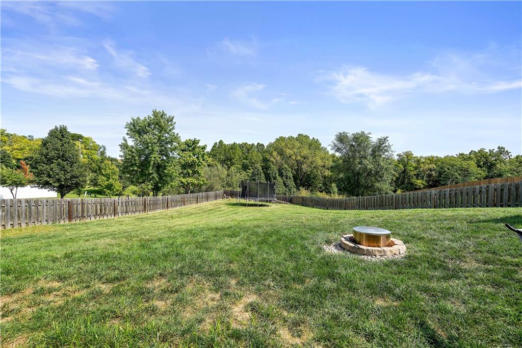 Privacy-fenced backyard with a fire pit and tree line in Weston, MO