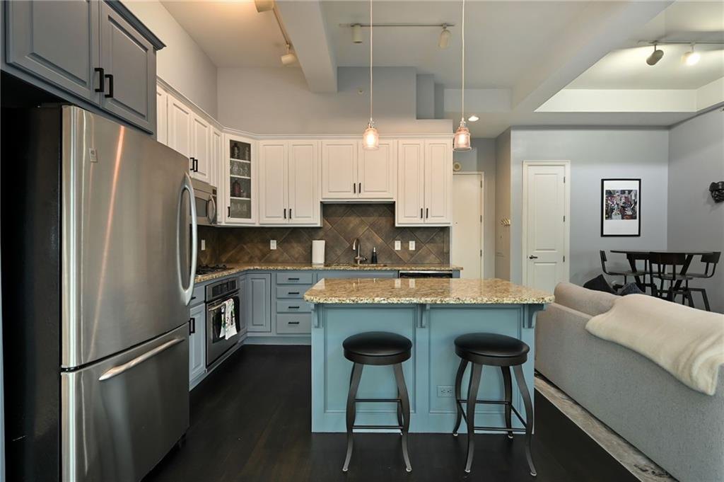 Kitchen with blue island, granite counters, stainless appliances and bar stools open to the living room, Wallstreet Towers, downtown Kansas City, MO
